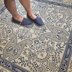 a woman standing on top of a blue and white floor next to an ornate rug