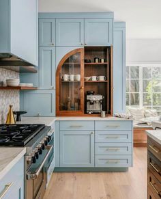 a kitchen with blue cabinets and wood flooring is shown in this image, there are two ovens on either side of the stove