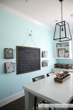 a kitchen with a chalkboard on the wall next to a white table and chairs