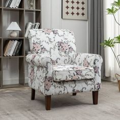 a white chair sitting in front of a book shelf filled with lots of books and plants