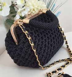 a black crocheted purse with gold chains on the handle and chain at the bottom