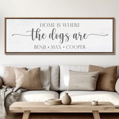 a living room with a couch, coffee table and large framed sign that says home is where the dogs are