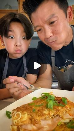 a man and child are looking at a plate of food with noodles on the side