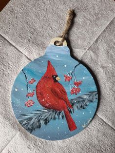 a ceramic ornament with a cardinal on it's side hanging from a rope