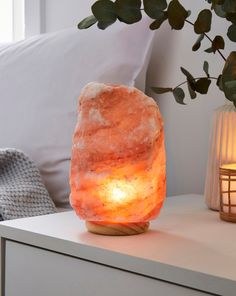 a rock lamp sitting on top of a white table next to a potted plant