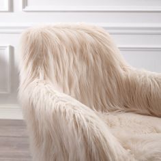 a white fur covered chair sitting on top of a hard wood floor