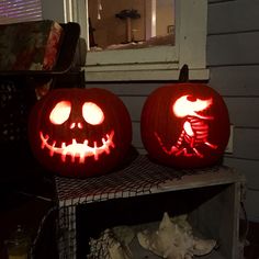 two carved pumpkins sitting on top of a shelf