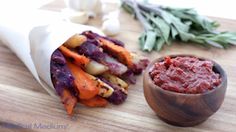 a wooden cutting board topped with veggies next to a bowl of red sauce