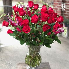 a vase filled with red roses on top of a wooden table