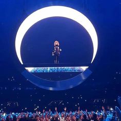 a person standing on top of a stage in front of an audience at a concert