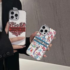 two people holding up their cell phones in front of them, one is wearing a suit and the other has a phone case