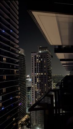 the city skyline is lit up at night with high rise buildings in the foreground