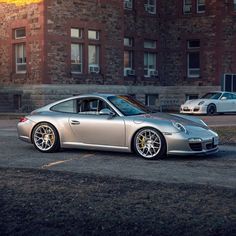 a silver sports car parked in front of a brick building