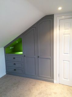 an attic bedroom with built - in closets and green lighting under the slanted roof