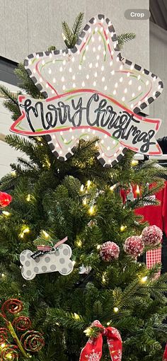 a christmas tree is decorated with ornaments and lights in front of a sign that says merry christmas