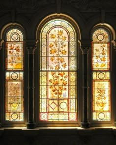 three stained glass windows in a building with columns and arches on each side, all depicting different types of flowers