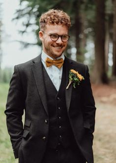 a man in a suit and bow tie smiles at the camera as he stands outside