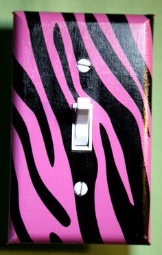 a pink and black light switch cover with zebra print on the side, in front of a green wall