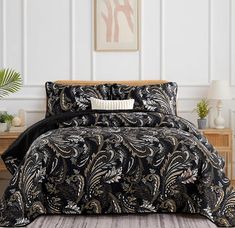 a black and gold comforter set on a bed in a room with white walls