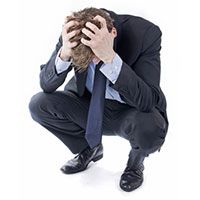 a man in a suit and tie holding his hands to his face while kneeling down