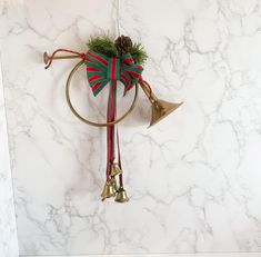 a christmas decoration hanging on the side of a wall with bells and a ribbon around it