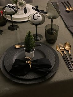 the table is set with black and gold place settings, silverware, and a small christmas tree