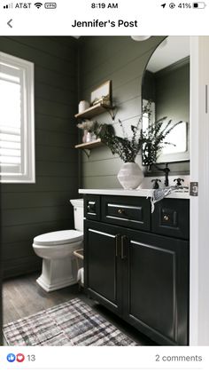 a white toilet sitting next to a bathroom sink under a mirror on top of a wooden floor