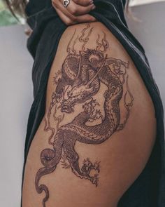 a woman with a dragon tattoo on her thigh