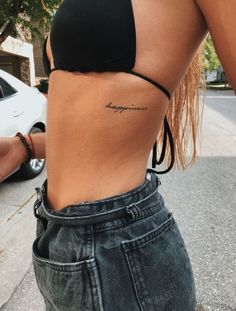 a woman with a tattoo on her lower back and the word happiness written in cursive writing