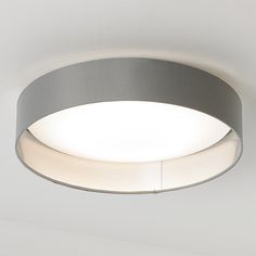 a circular light fixture mounted on the ceiling in a room with white walls and flooring