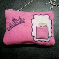 a pink pillow with a crown on it and a string hanging from the side that is attached to a hook