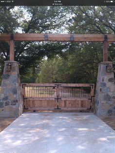 a gated in area with stone pillars and gates on both sides, surrounded by trees