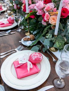 the table is set with pink napkins, silverware and roses in vases