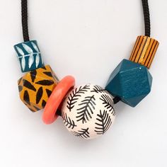 a necklace made out of wooden beads and other colorful objects on a black cord with a white background