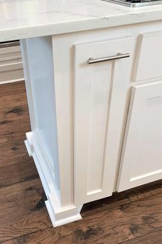 a white kitchen island with an oven and sink in the center, on top of a hard wood floor