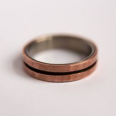 two wedding bands made out of copper and silver are sitting on a white table top