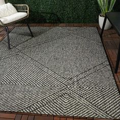 a black and white area rug sitting on top of a wooden floor next to a chair