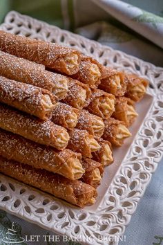 a white plate topped with lots of pastries covered in powdered sugar on top of a table