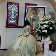 a woman in a ball gown sitting on the floor next to a vase with flowers