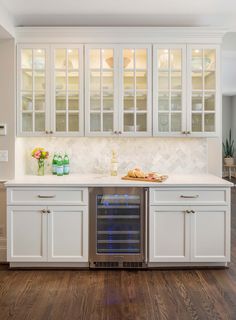 a kitchen with white cabinets and wood floors