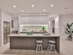 a kitchen with two stools next to an island