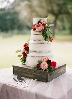 a wedding cake sitting on top of a wooden box next to a knife and fork