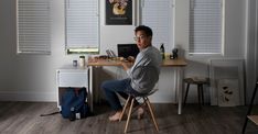 a man sitting at a desk with a laptop in front of him on his lap