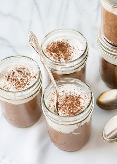 four jars filled with chocolate pudding and topped with powdered sugar