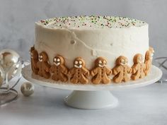 a white cake with frosting and decorated gingerbreads