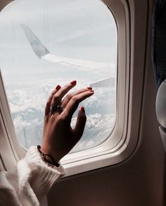 a woman's hand reaching out an airplane window