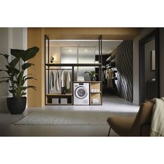 a room that has a washer and dryer in it, next to a potted plant