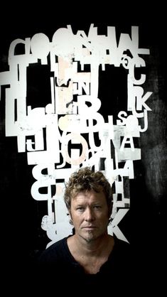 a man standing in front of a black and white wall with letters all over it