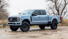 a silver truck parked on top of a dirt field