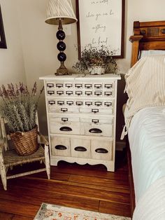 a white dresser sitting next to a bed on top of a wooden floor